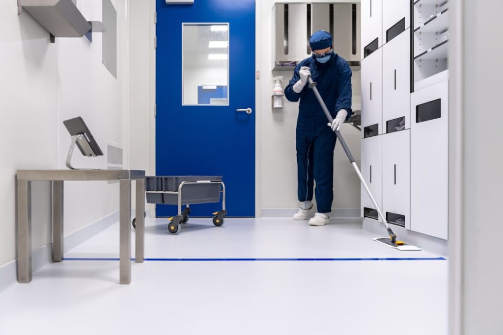 Reinigungskraft mit Maske und Leiter bereitet Höhenarbeit vor