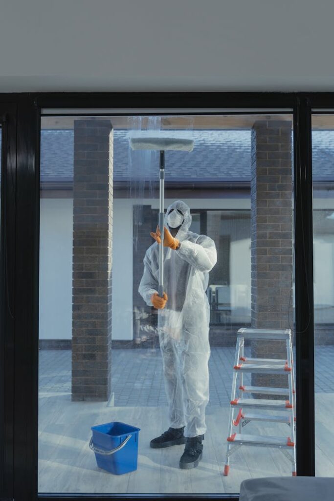Reinigungskraft putzt streifenfrei eine große Glasscheibe