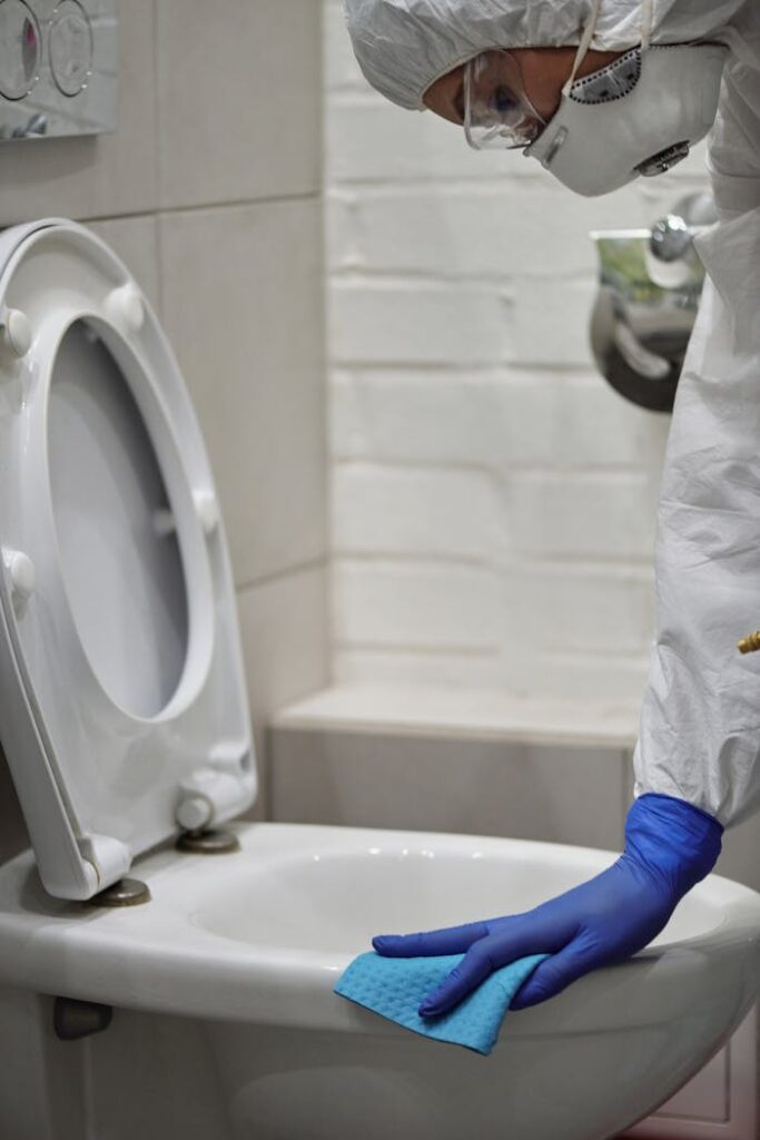 Reinigungskraft reinigt Toilettenschüssel im Sanitärbereich